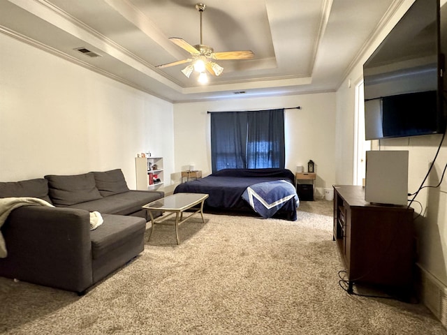 carpeted bedroom with a tray ceiling, ceiling fan, and ornamental molding