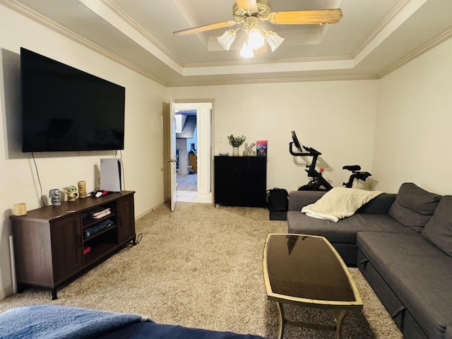 living room featuring ceiling fan, a raised ceiling, ornamental molding, and light carpet