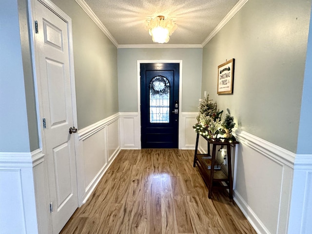 entryway with crown molding, light hardwood / wood-style floors, and a textured ceiling