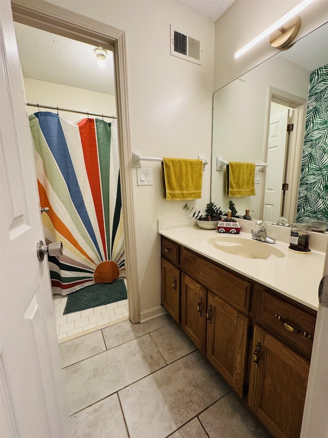 bathroom with a textured ceiling, vanity, and tile patterned floors