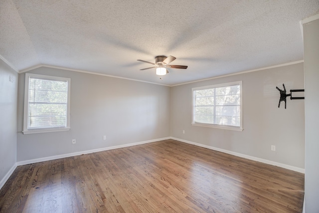 unfurnished room with a textured ceiling, ornamental molding, vaulted ceiling, and hardwood / wood-style flooring