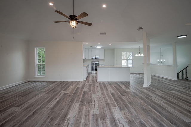 unfurnished living room with vaulted ceiling, hardwood / wood-style floors, and ceiling fan with notable chandelier