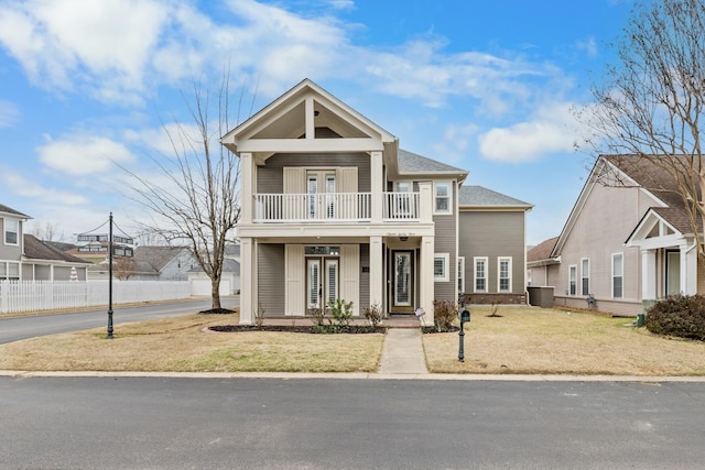 view of front facade with a porch, a balcony, french doors, and a front yard