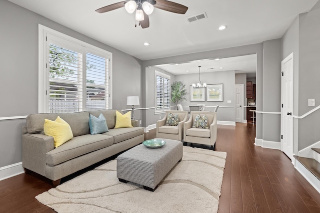 living room featuring ceiling fan with notable chandelier and dark hardwood / wood-style flooring