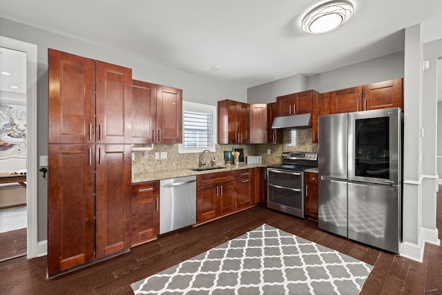 kitchen featuring appliances with stainless steel finishes, backsplash, dark hardwood / wood-style flooring, light stone counters, and sink