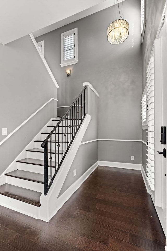 stairway featuring hardwood / wood-style flooring, a notable chandelier, and a towering ceiling