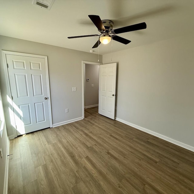 unfurnished bedroom with ceiling fan, wood finished floors, visible vents, and baseboards