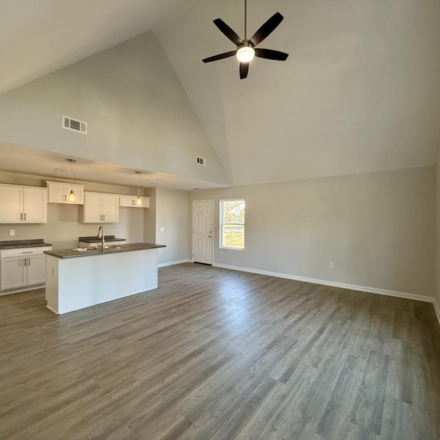 kitchen featuring dark countertops, visible vents, open floor plan, and a sink