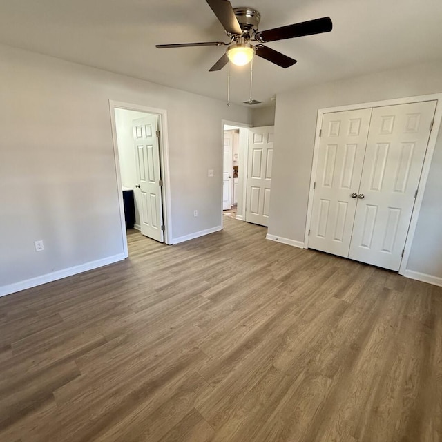 unfurnished bedroom featuring a ceiling fan, dark wood-style flooring, a closet, and baseboards