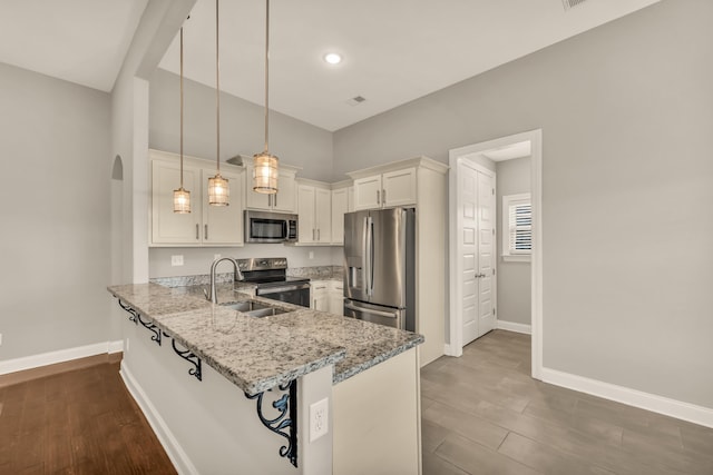 kitchen with white cabinetry, sink, hanging light fixtures, stainless steel appliances, and kitchen peninsula