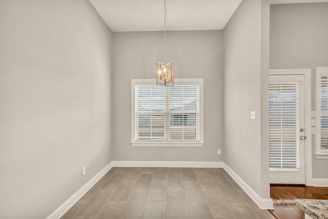 unfurnished dining area with light wood-type flooring and an inviting chandelier