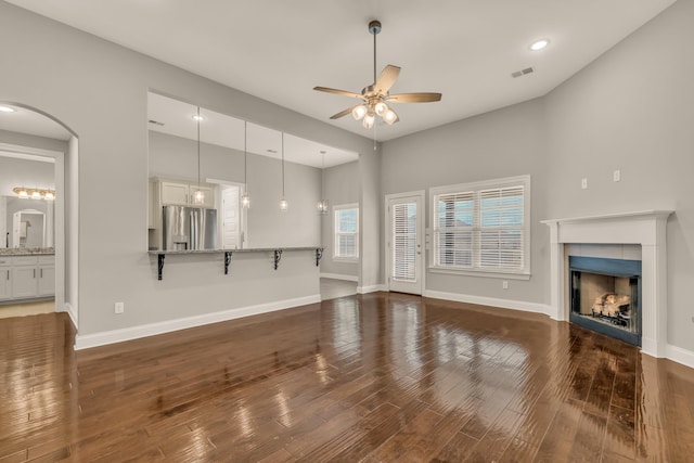 unfurnished living room featuring ceiling fan, a fireplace, and dark hardwood / wood-style floors