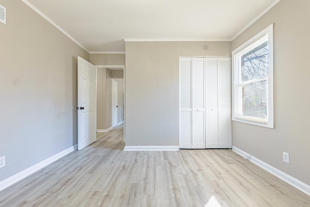 unfurnished bedroom with light hardwood / wood-style floors, ornamental molding, and a closet