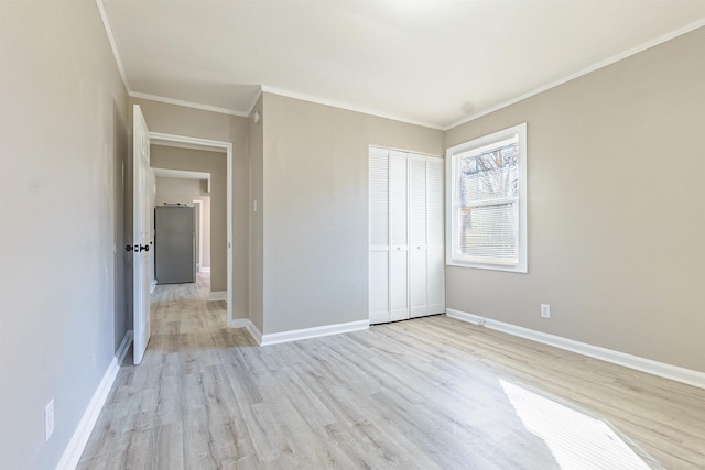 unfurnished bedroom with stainless steel fridge, crown molding, and light hardwood / wood-style flooring