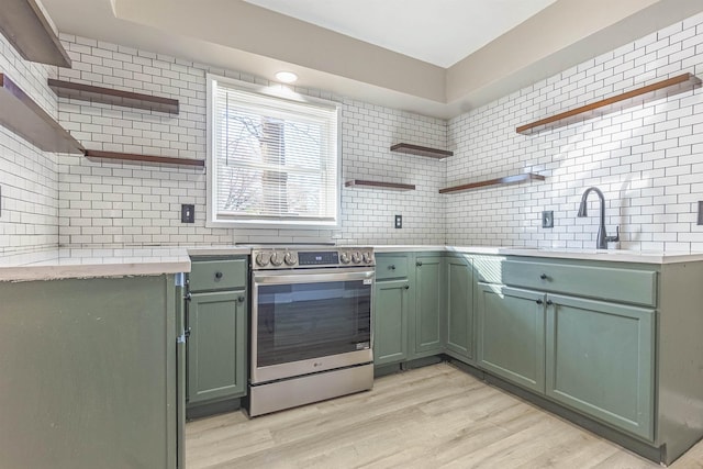 kitchen with electric range, tasteful backsplash, green cabinetry, and light hardwood / wood-style floors