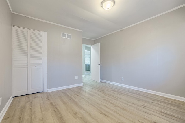 unfurnished bedroom featuring light hardwood / wood-style floors, ornamental molding, and a closet