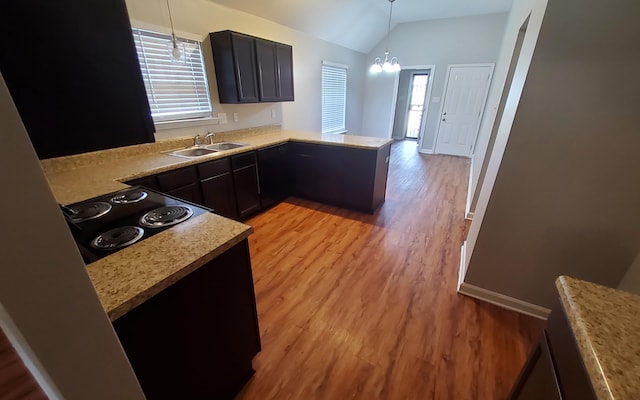 kitchen with sink, cooktop, kitchen peninsula, a chandelier, and lofted ceiling