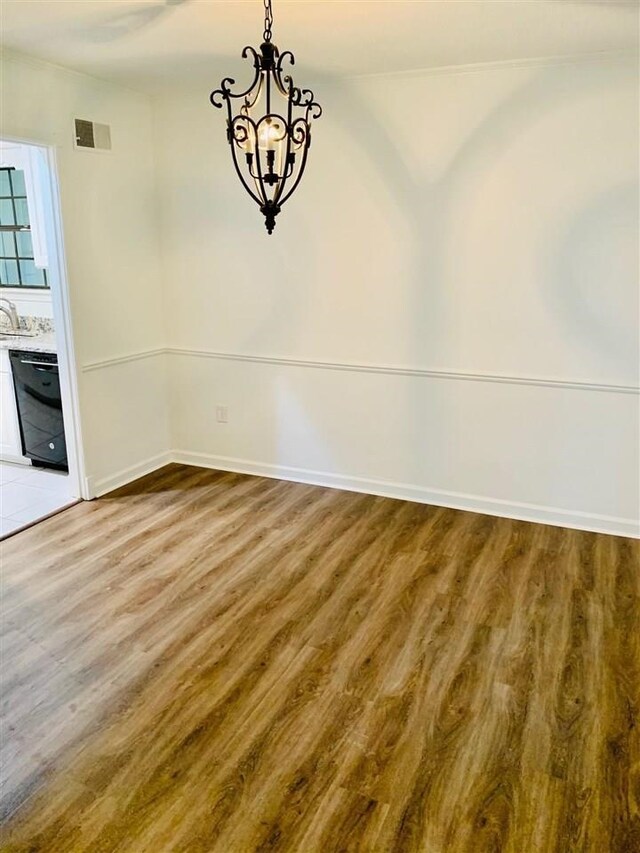 unfurnished dining area with hardwood / wood-style floors, sink, and a chandelier