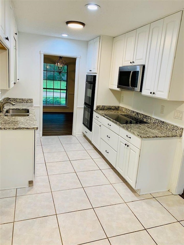 kitchen featuring black appliances, white cabinetry, sink, and dark stone counters