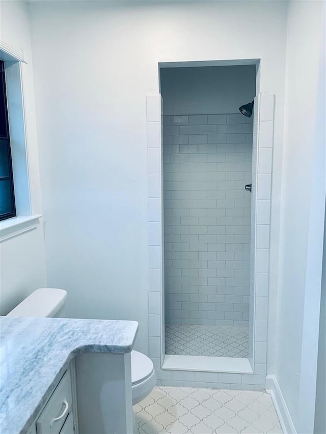 bathroom featuring tile patterned flooring, vanity, toilet, and a tile shower