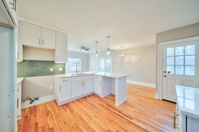 kitchen featuring kitchen peninsula, ceiling fan, decorative light fixtures, light hardwood / wood-style floors, and white cabinetry