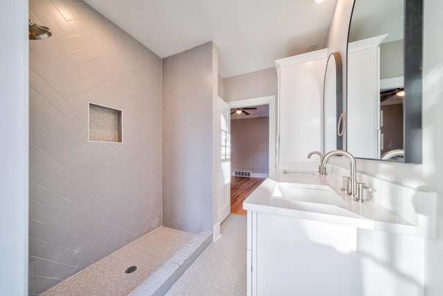 bathroom with a tile shower, ceiling fan, and vanity