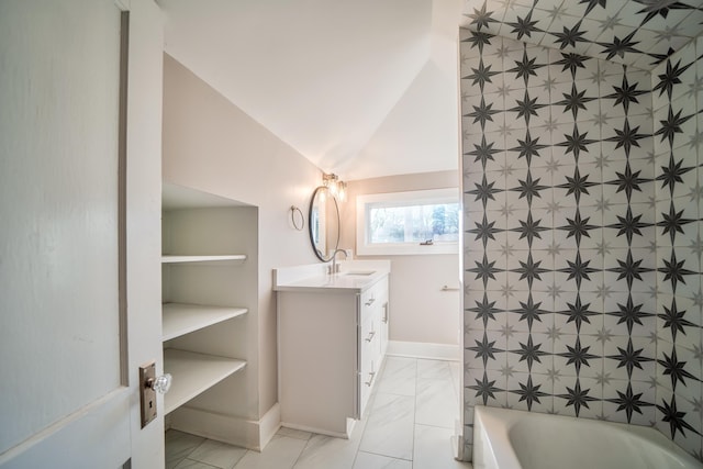 bathroom with a bathing tub, vanity, and lofted ceiling