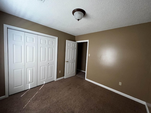 unfurnished bedroom with a closet, a textured ceiling, and dark colored carpet