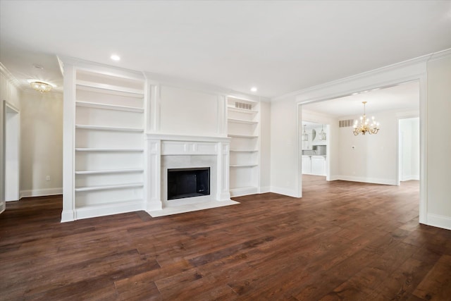 unfurnished living room with an inviting chandelier, crown molding, built in shelves, a fireplace, and dark hardwood / wood-style flooring