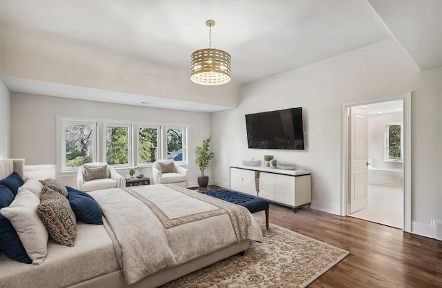 bedroom featuring hardwood / wood-style floors, vaulted ceiling, connected bathroom, and a chandelier