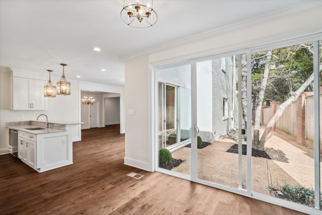 doorway to outside featuring dark hardwood / wood-style flooring, crown molding, sink, and a chandelier