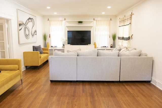 living room with hardwood / wood-style flooring, plenty of natural light, and ornamental molding