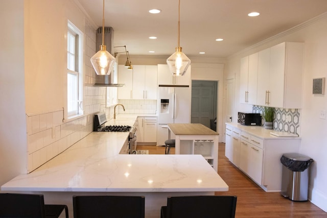 kitchen featuring stainless steel range with gas cooktop, decorative light fixtures, white cabinetry, and white refrigerator with ice dispenser