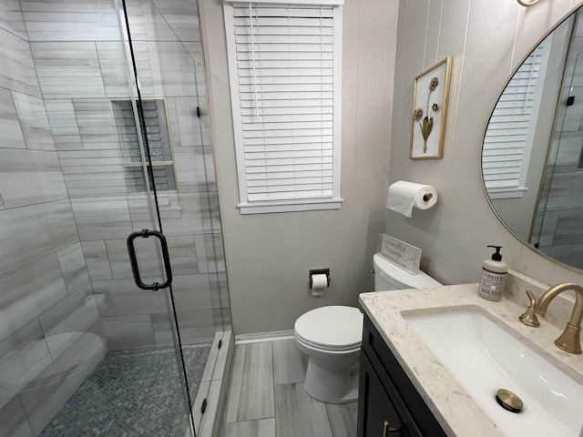 bathroom featuring vanity, toilet, and a shower with shower door