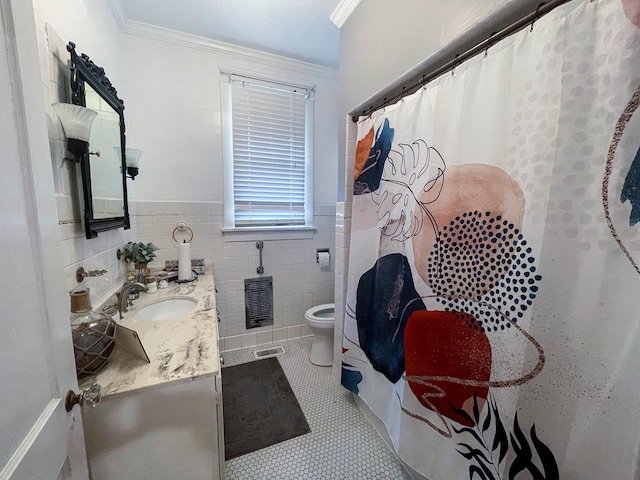 bathroom with tile patterned floors, ornamental molding, vanity, tile walls, and toilet