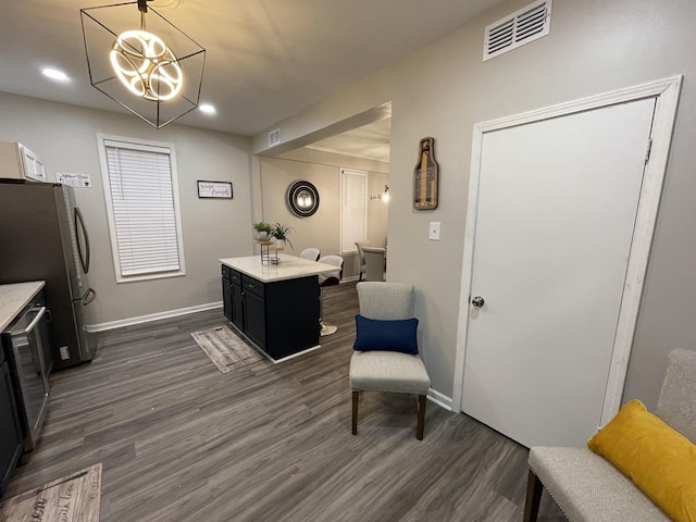 interior space featuring stainless steel refrigerator, dark wood-type flooring, decorative light fixtures, and a notable chandelier