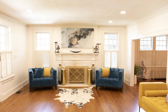 sitting room featuring hardwood / wood-style floors, radiator heating unit, a fireplace, and ornamental molding