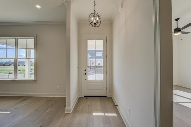 doorway featuring crown molding, ceiling fan with notable chandelier, and light wood-type flooring