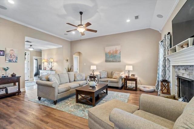 living room with hardwood / wood-style flooring, ceiling fan, ornamental molding, and a fireplace