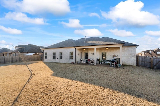 rear view of property featuring a lawn and ceiling fan