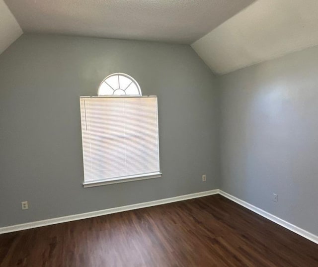 unfurnished room featuring a textured ceiling, dark hardwood / wood-style flooring, and lofted ceiling