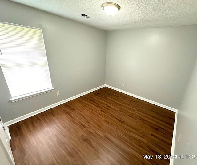 unfurnished room with dark wood-type flooring and a textured ceiling