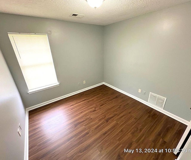 unfurnished room featuring a textured ceiling and dark wood-type flooring