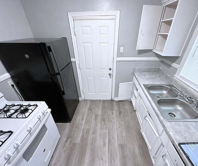 kitchen featuring white cabinets, light wood-type flooring, white gas range, and sink