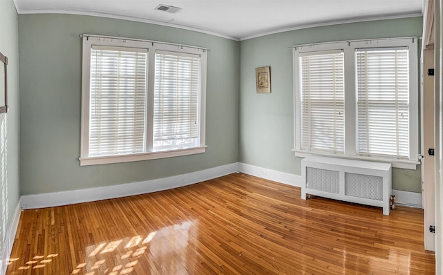 spare room featuring plenty of natural light, radiator heating unit, and light hardwood / wood-style flooring