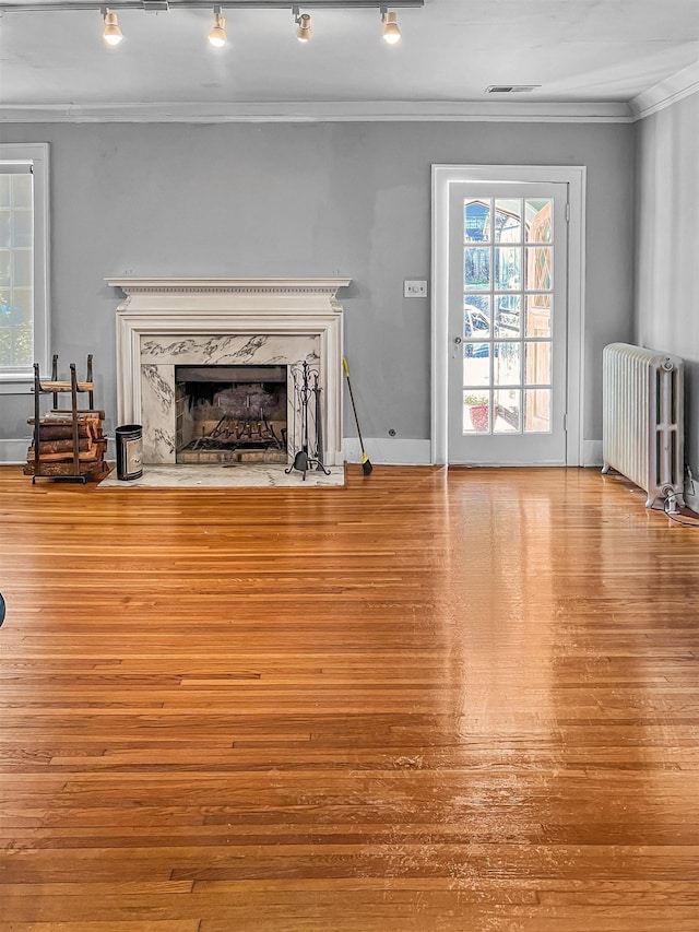 unfurnished living room featuring radiator heating unit, crown molding, and a premium fireplace