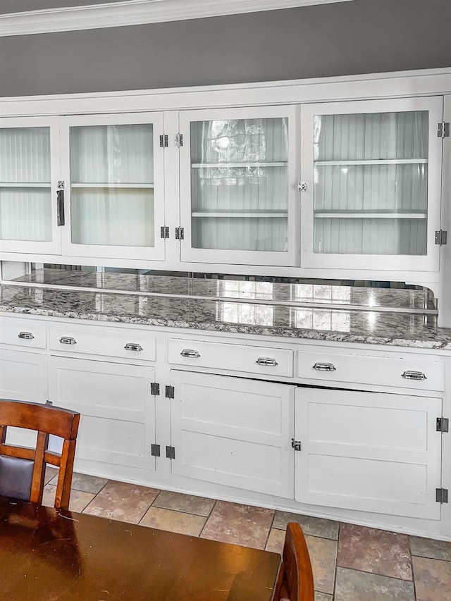 bar with crown molding, white cabinets, and light stone countertops