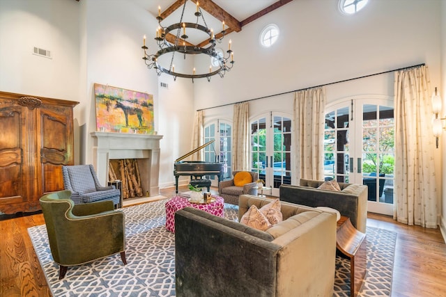 living room with french doors, hardwood / wood-style flooring, an inviting chandelier, and a high ceiling