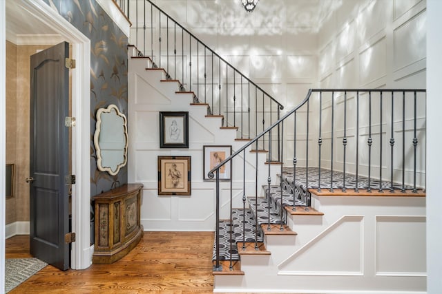 stairs with wood-type flooring and crown molding