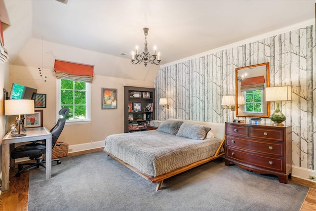 bedroom featuring hardwood / wood-style floors, lofted ceiling, and an inviting chandelier